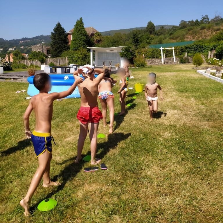 Crianzas participando en xogos de auga ao aire libre durante unha actividade de verán.